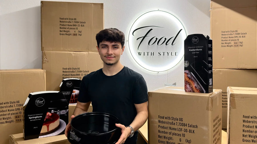 Emre Tuncer mit der Springform von Food with Style vor dem leuchtenden Logo und Kartons mit Backformen